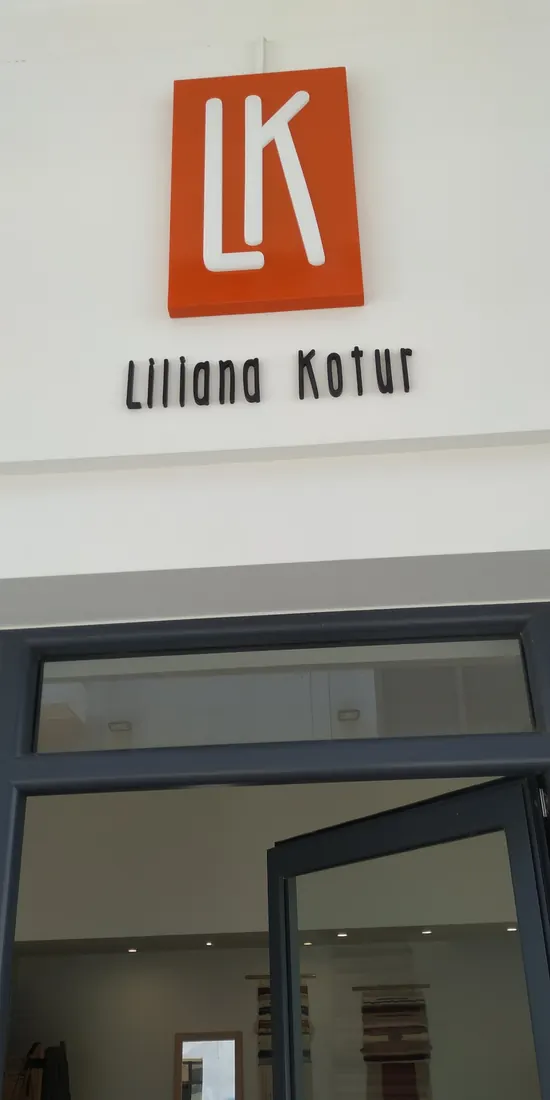 Επιγραφή με πορτοκαλί ταμπέλα και λευκό μονόγραμμα, και ξεχωριστά μαύρα γράμματα πάνω από την είσοδο